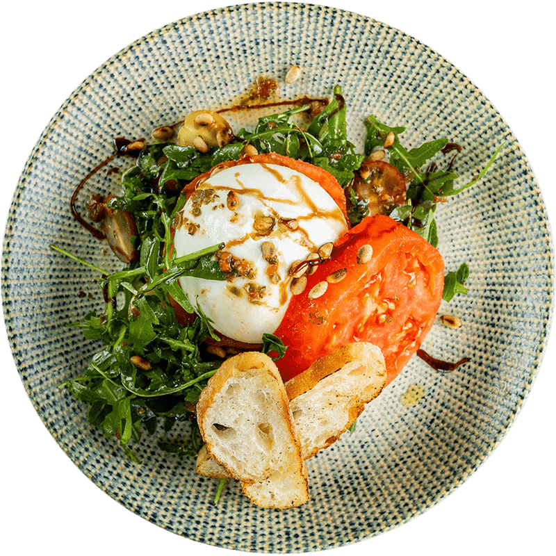 Салата с яйца, домати и рукола, поднесена в стилна чиния.